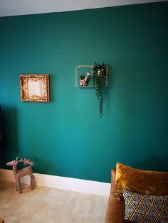 a living room painted in teal and gold with two pictures hanging on the wall