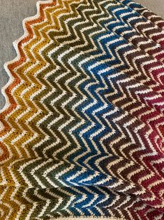 four different colors of knitted blankets on top of each other, one is multicolored