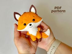 a hand holding a small stuffed animal that looks like a fox