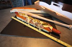 a hot dog on a bun with mustard and ketchup next to a measuring tape