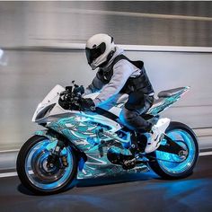 a man riding on the back of a blue and white motorcycle