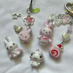 some cute little key chains are laying on a white sheet with hearts and other charms