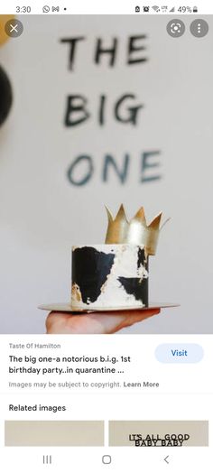 someone is holding a small cake with black and white frosting, topped with a crown