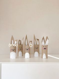 four paper bags with bunny ears and flowers in them on top of a white table