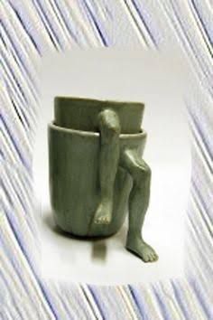 there is a small green cup with a person sitting in the cup and another figure standing behind it