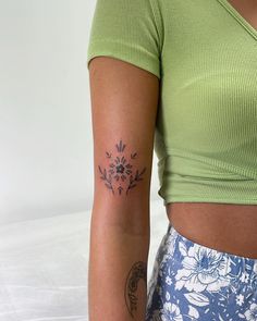 a woman with a flower tattoo on her left arm and right arm behind her back