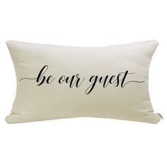 a white pillow with the words be our guest printed on it and black lettering in cursive font