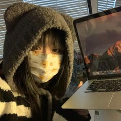 a woman wearing a face mask while using a laptop