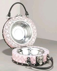 a pink and black purse sitting on top of a white table next to a silver bowl