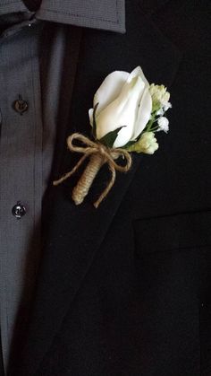 a boutonniere with white flowers is tied to the lapel of a suit