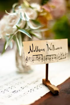 there is a small note with music notes on it next to a vase filled with flowers