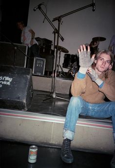 a man sitting on top of a stage with his hands in the air