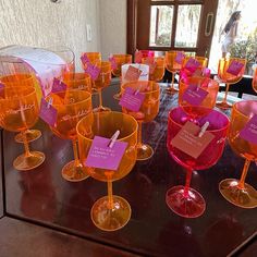 there are many wine glasses on the table with pink tags in them and one has a note pinned to it