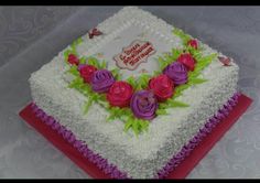 a birthday cake decorated with flowers on a red and white tableclothed table cloth