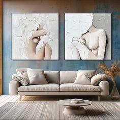 two paintings on the wall of a living room with a couch and coffee table in front of it