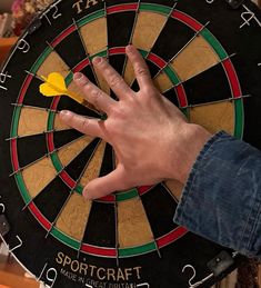 a person's hand on top of a dart board