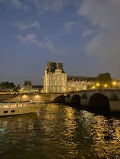 a bridge that is over some water with buildings in the background and lights on it