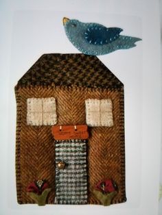 a blue bird sitting on top of a brown house with two windows and a door