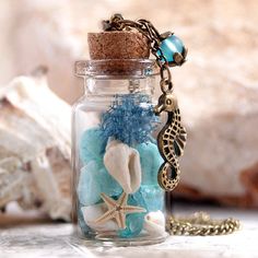 a glass jar filled with sea shells and seashells next to a gold chain