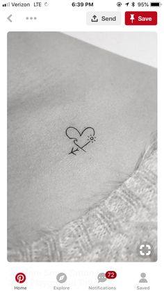 a small heart tattoo on the back of a woman's stomach, with an arrow in