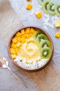 a bowl filled with rice and sliced kiwi on top of a table next to silverware