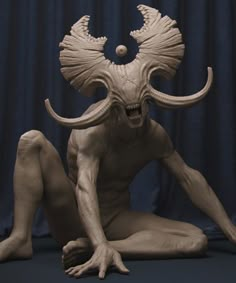 a sculpture of a demon sitting on the ground