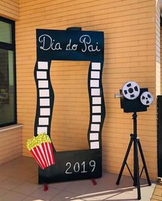 a movie themed display in front of a building with a popcorn bucket and film camera