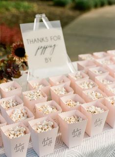 there are many small pink boxes on the table with tags that say thank you by