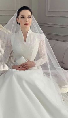 a woman in a white wedding dress sitting on a couch