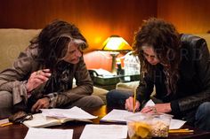 two women sitting at a table with papers and pens in front of them on the coffee table