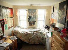 a bedroom with an unmade bed and lots of clutter on the desks