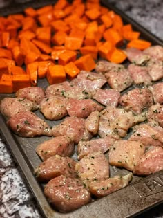 some meat and vegetables are on a baking sheet in the middle of a counter top