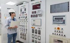 a man is standing in front of some control panels and holding a piece of paper