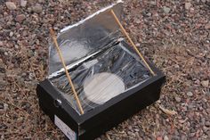 an open box sitting on top of a gravel covered ground next to grass and rocks