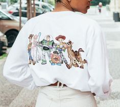 a woman with her back to the camera, wearing a white sweatshirt that has cartoon characters on it