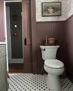 a white toilet sitting inside of a bathroom next to a wall with pictures on it