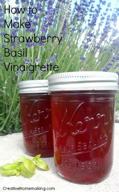 two mason jars filled with homemade strawberry basil vinaigreate sitting on sand next to lavender flowers