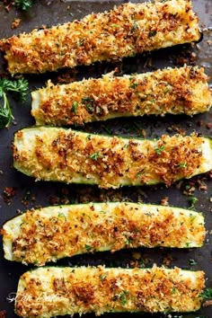 four pieces of breaded food on a pan with parsley and seasoning sprinkles