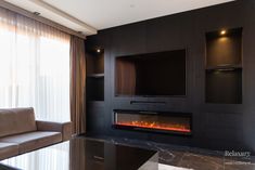 a living room with a couch, television and fire place in the fireplace that is built into the wall