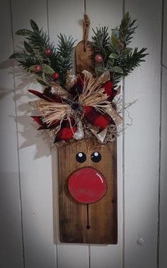 a wooden reindeer head hanging on the wall next to a christmas wreath and door hanger