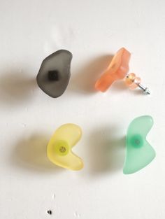 three different colored plastic buttons on a white surface with holes in the middle and one has an ear hole