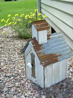 an old bird house is sitting on the gravel