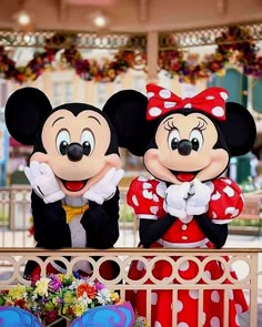 two mickey and minnie mouse characters standing next to each other