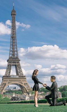 a man kneeling down next to a woman in front of the eiffel tower