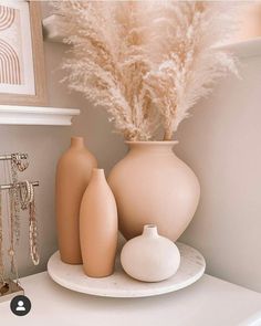 some vases and other decorative items on a white shelf in the corner of a room