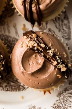 three cupcakes with chocolate frosting and sprinkles on a plate