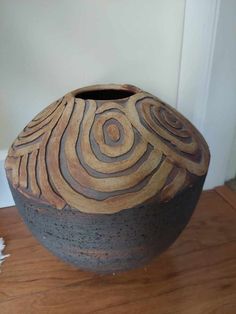 a brown and black vase sitting on top of a wooden floor