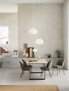 a dining room table with four chairs and two lamps hanging from the ceiling above it