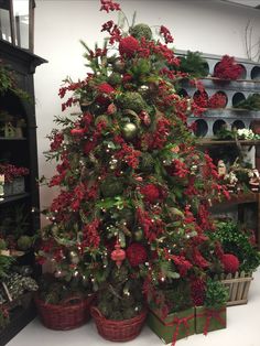 a christmas tree with red flowers and ornaments in baskets on the floor next to it