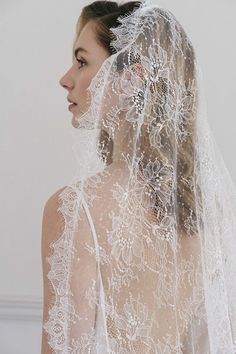 a woman wearing a wedding veil with flowers on the side and back of her head